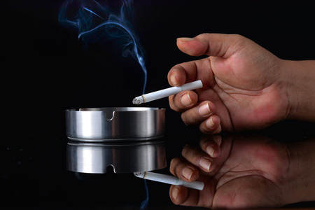 hand holding cigarette on black backgroundの写真素材