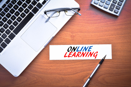 Laptop with glasses, pen and calculator with text ONLINE LEARNINGの写真素材