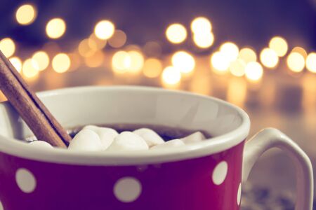 Cocoa with marshmallows with lights on christmas tree background.の写真素材