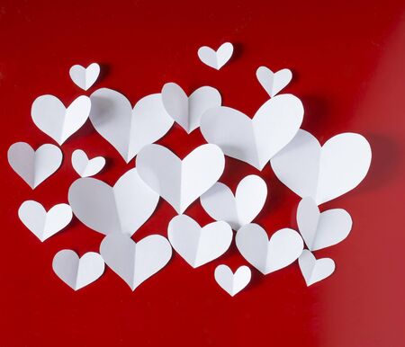 Valentine's Day vintage background, white paper hearts on red background.の写真素材