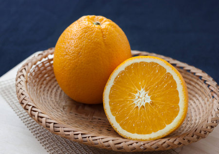 Fresh chopped oranges in basket with dark blue backgroundの写真素材