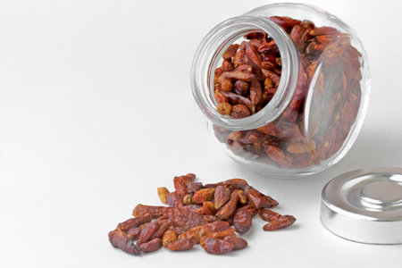 Dry chilis in small jar on white backgroundの写真素材