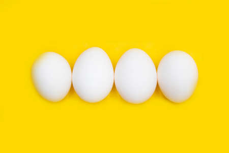 white chicken egg isolated on yellow backgroundの写真素材