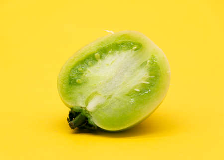 Fresh green unripe tomatoes isolated on yellow background