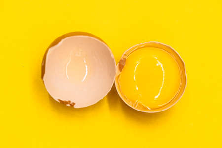 whole eggs and broken isolated on yellow background,の写真素材