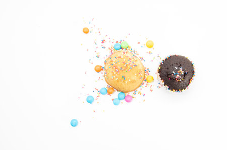 Chocolate muffin and yellow muffin cupcake design by colorful sprinkle isolated on white background, top viewの写真素材