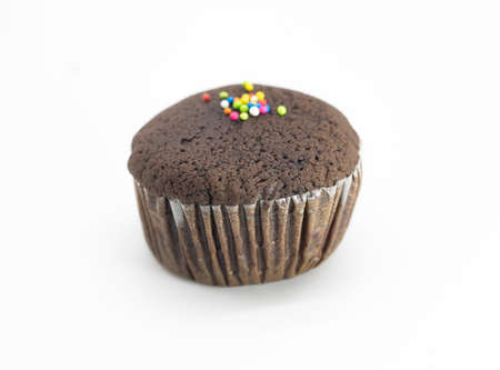 Chocolate muffin in brown paper with sprinkle isolate on whiteの写真素材