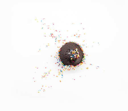 Chocolate muffin in brown paper with sprinkle isolate on whiteの写真素材