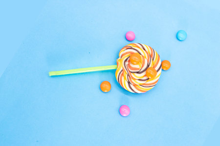 Colorful lollipop with candy pills isolated on blue background