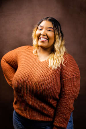 Black girl wearing burnt orange sweater with brown backdrop, Black girl wearing a sweater, Mixed girl wearing burnt orange sweater with brown backdrop, Mixed girl wearing a sweaterの写真素材