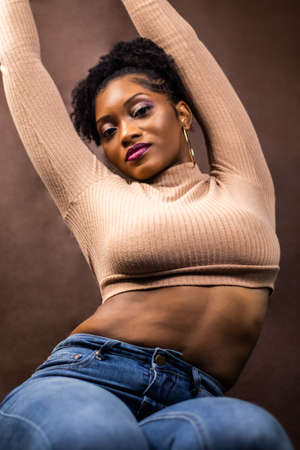 Black woman posing in a brown sweater, Black woman with natural hair, Woman wearing brown sweater and blue jeans, Woman wearing ribbed open back long sleeve cropped sweater, Woman posing in Miami, FLの写真素材