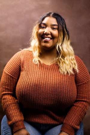 Black girl wearing burnt orange sweater with brown backdrop, Black girl wearing a sweater, Mixed girl wearing burnt orange sweater with brown backdrop, Mixed girl wearing a sweaterの写真素材