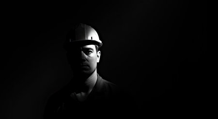 Portrait of a young man in a hardhat on a dark backgroundの写真素材