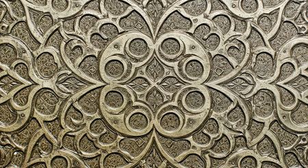 Close up detail of a carved metal plate with ornamental pattern.