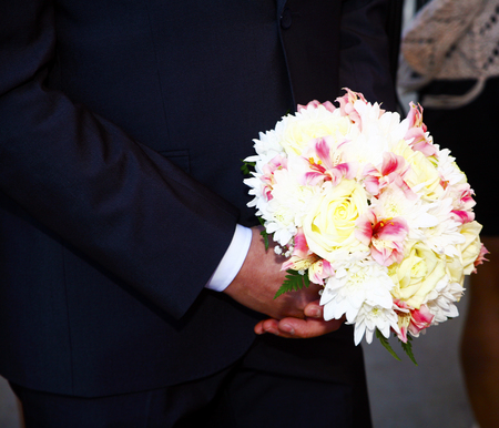 beautiful wedding bouquet of white roses in hands of newlywedsの写真素材
