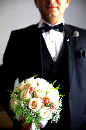 beautiful wedding bouquet of white roses in hands of newlywedsの写真素材