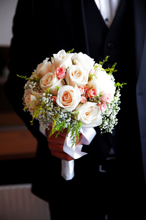 beautiful wedding bouquet of white roses in hands of newlywedsの写真素材