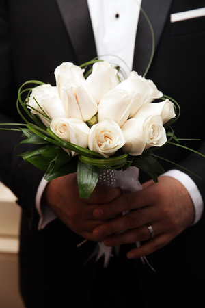 beautiful wedding bouquet of white roses in hands of newlywedsの写真素材
