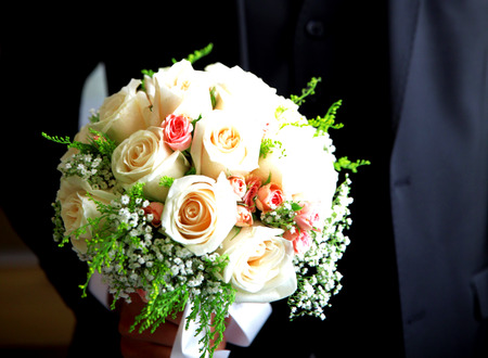 beautiful wedding bouquet of white roses in hands of newlywedsの写真素材