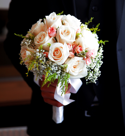 beautiful wedding bouquet of white roses in hands of newlywedsの写真素材