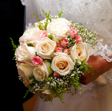 beautiful wedding bouquet of white roses in hands of newlywedsの写真素材