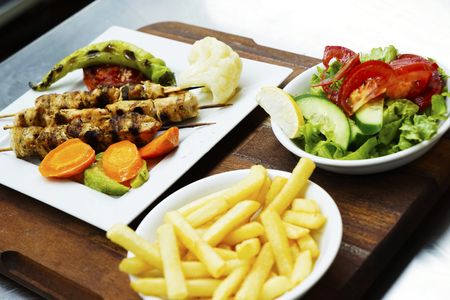 dish with fried meat potatoes tomatoes cucumbers greens and spicy seasoningsの写真素材