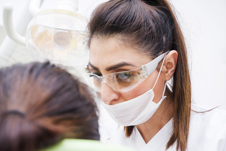 Female dentists examining and working on young male patient.Dentist's office.の写真素材