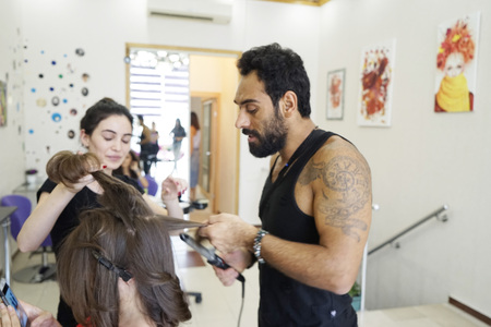 beauty and people concept - happy young woman with hairdresser coloring hair at salonのeditorial素材
