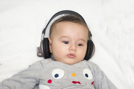 baby with headphone lies on back, close upの写真素材