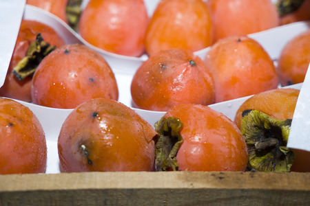 ripe orange persimmon lies on white paper in a box for sale in a store,の写真素材