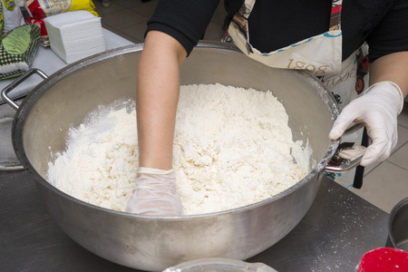 women's hands in rubber gloves mix flour in an iron pan in the table