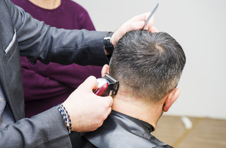men's hairstyling and haircutting with hair clipper in a barber shop or hair salon,close upの写真素材