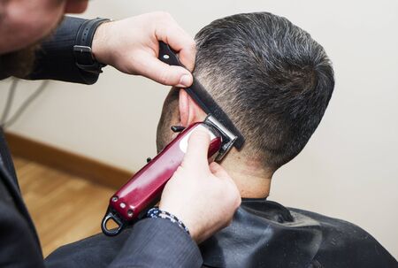 men's hairstyling and haircutting with hair clipper in a barber shop or hair salon,close up
