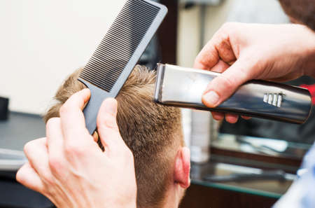 men's hairstyling and haircutting with hair clipper in a barber shop or hair salon,close upの写真素材