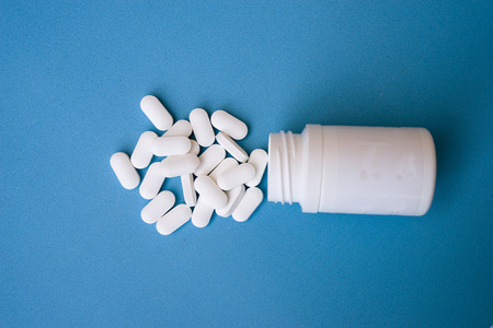 medicine white tablets and medicine bottle isolated on blue background. Top view