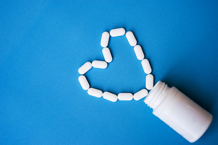 medicine white tablets and medicine bottle isolated on blue background. Top view