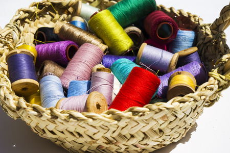 Wicker basket with balls of knitting yarn on white background, close up