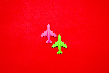 Flat lay of miniature toy airplane on pastel red background minimal trip and travel creative...