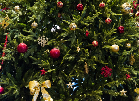 Close up of Christmas tree with ornaments of baubles, snowflakes, teddy bears, sleighs, gingerbread house, pine cones and lights.の写真素材