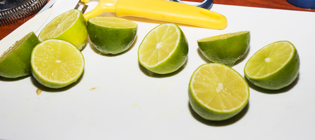 Half of the lime and lime slices are lying on the white wooden background. Citrus food photo. Green,...