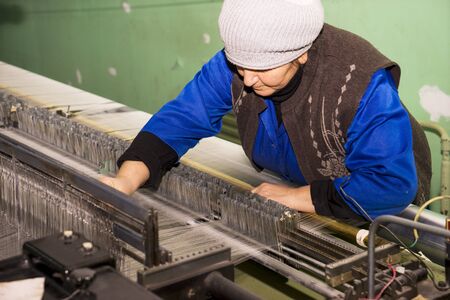 BAKU, AZERBAIJAN, 20 FEBRUARY 2018 : female labor working at the local looming factory with machinery equipment background to produce the colorful silk thread for the textile industryのeditorial素材