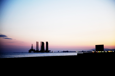 Silhouette of bridge connected offshore oil production platforms at oil field during sunsetの写真素材