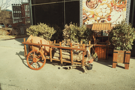 an old wooden cart with a clay jug and firewood stands in the yardの写真素材