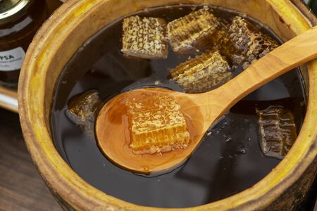 Honey spoon buried in a barrel of fragrant fresh honey. Close-up.の写真素材