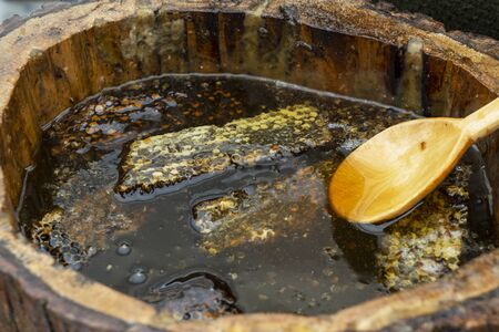 Honey spoon buried in a barrel of fragrant fresh honey. Close-up.