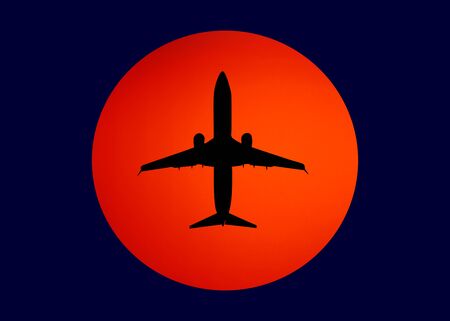 black silhouette of the plane against the orange sun in the blue sky