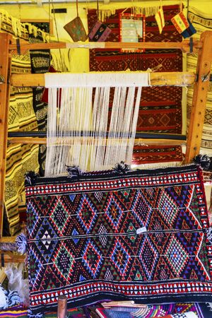 A traditional rug being woven on a carpet vertical loom, showing wool pile under tension, foundation, warp and weft.の写真素材