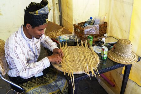 Baku, Azerbaijan-June 20, 2019: male master weaves straw hat.