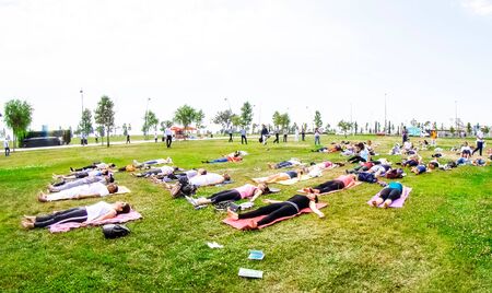Baku, Azerbaijan, may 20, 2019: men and women practice yoga in a Park on a green glade.のeditorial素材