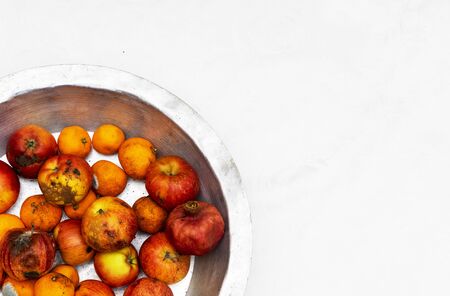 Rotten, spoiled apples and tangerines on an iron pan on a white backgroundの写真素材